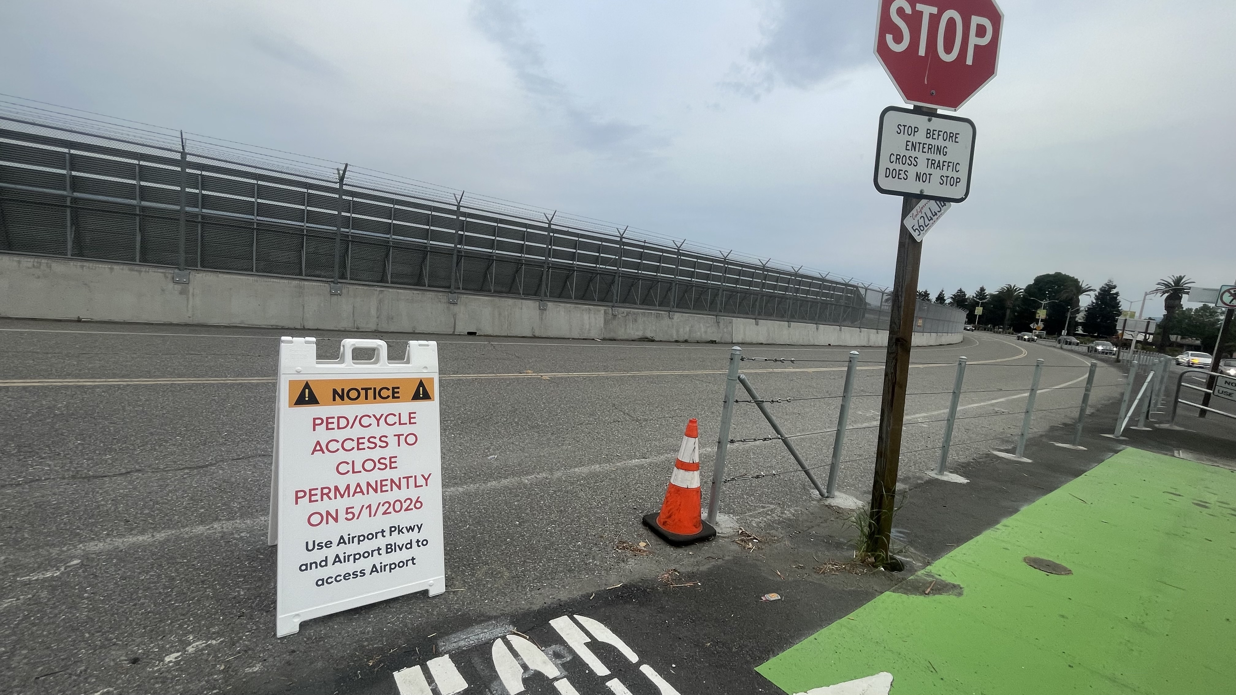 A-frame notice at the roadside: permanent closure of pedestrian and bicycle access; directs travelers to Airport Parkway and Airport Boulevard
